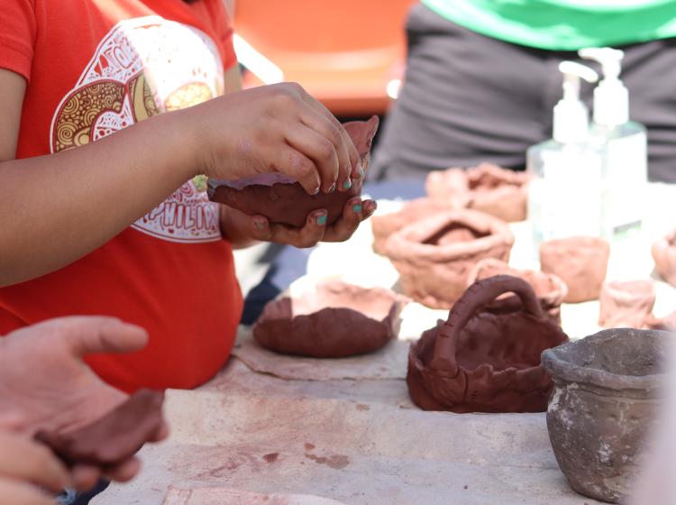 A visitor at the 2019 Archaeology Roadshow in Portland makes a ceramic pot at a students exhibit; photo by Kathryn Berg