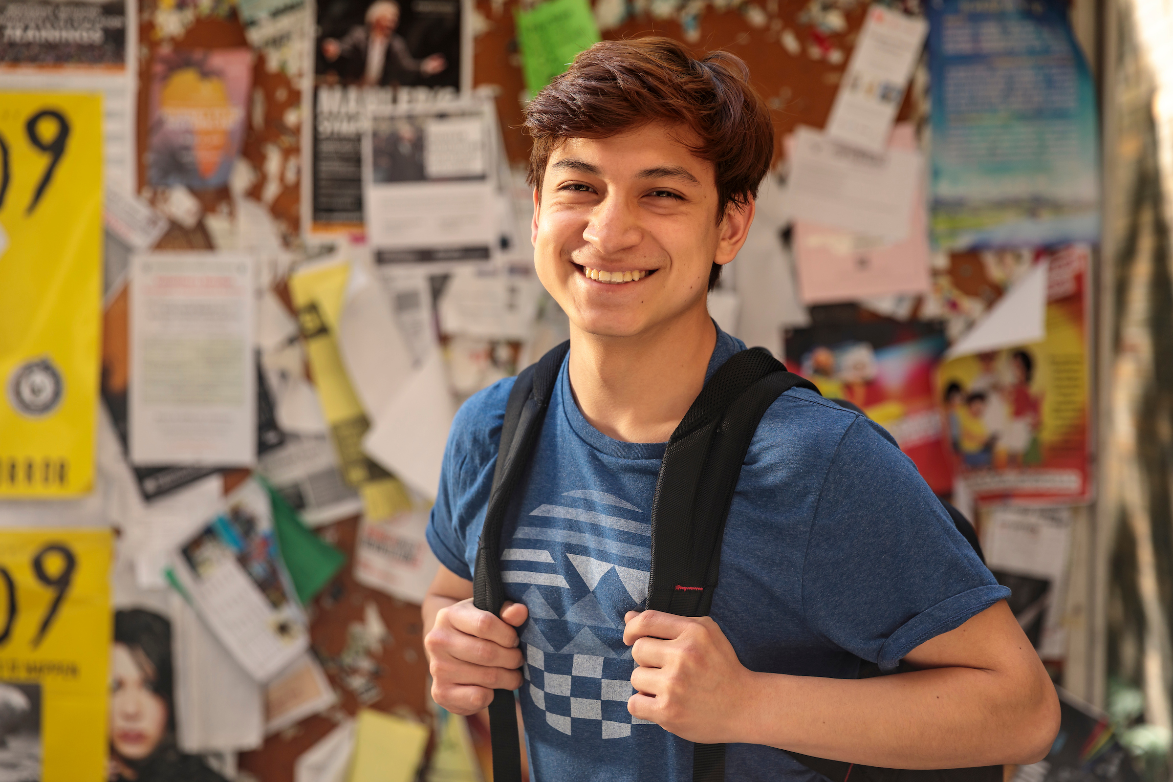 student smiling in front of bulletin board