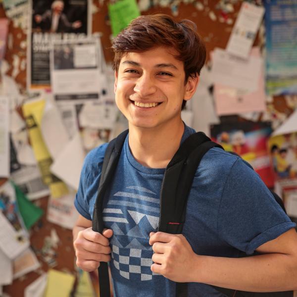 student smiling in front of bulletin board