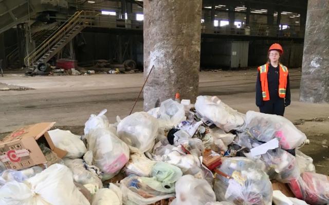 woman standing next to a pile of trash that was picked up