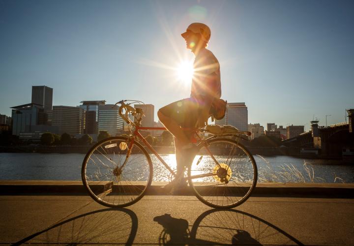 Student riding bicycle with Portland skyline in background