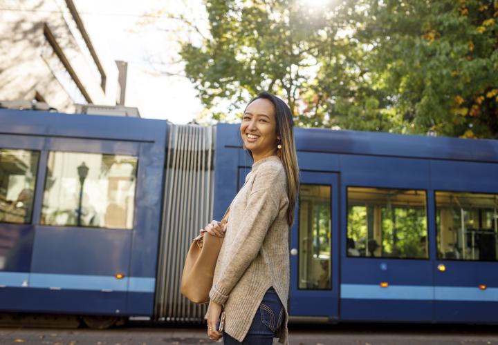 Image shows a Communication student smiling as a Streetcar passes by in the background.
