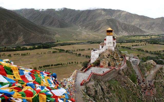 View of Tibetan peace flags and monastery in the mountains.