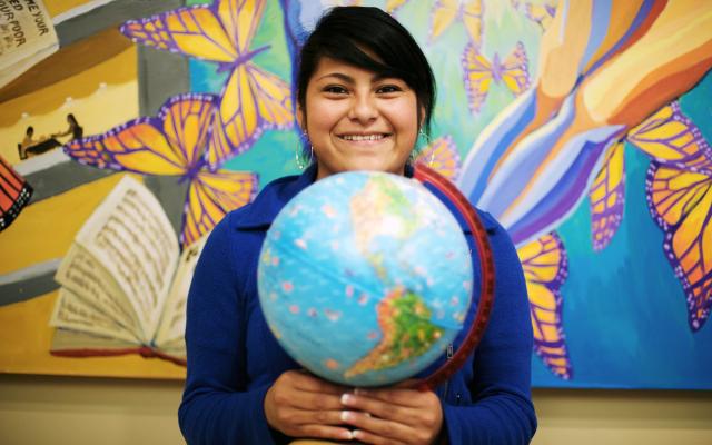 A student from the multicultural center holding a globe.