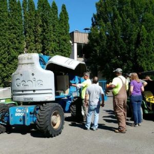 A group of training attendees and the instructor around a boom lift, performing an inspection