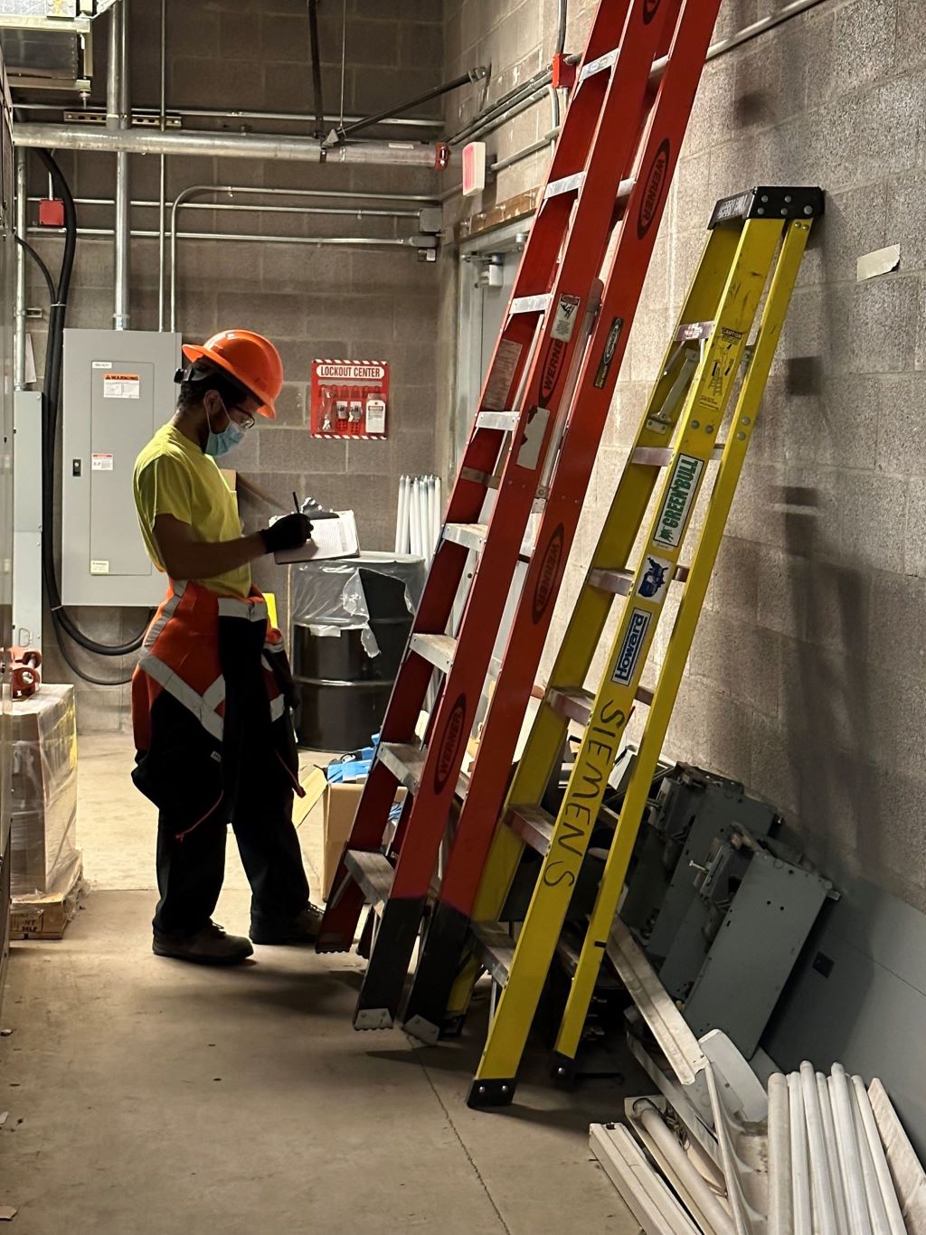 Worker in Personal Protective Equipment inspecting a ladder