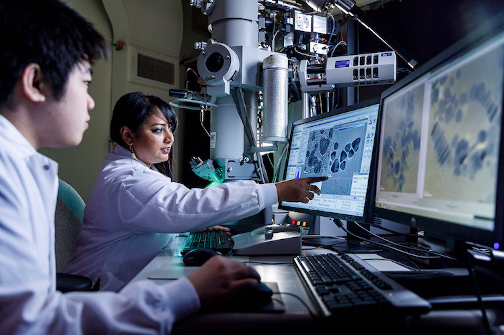 researcher and student look at cells on computer in lab setting