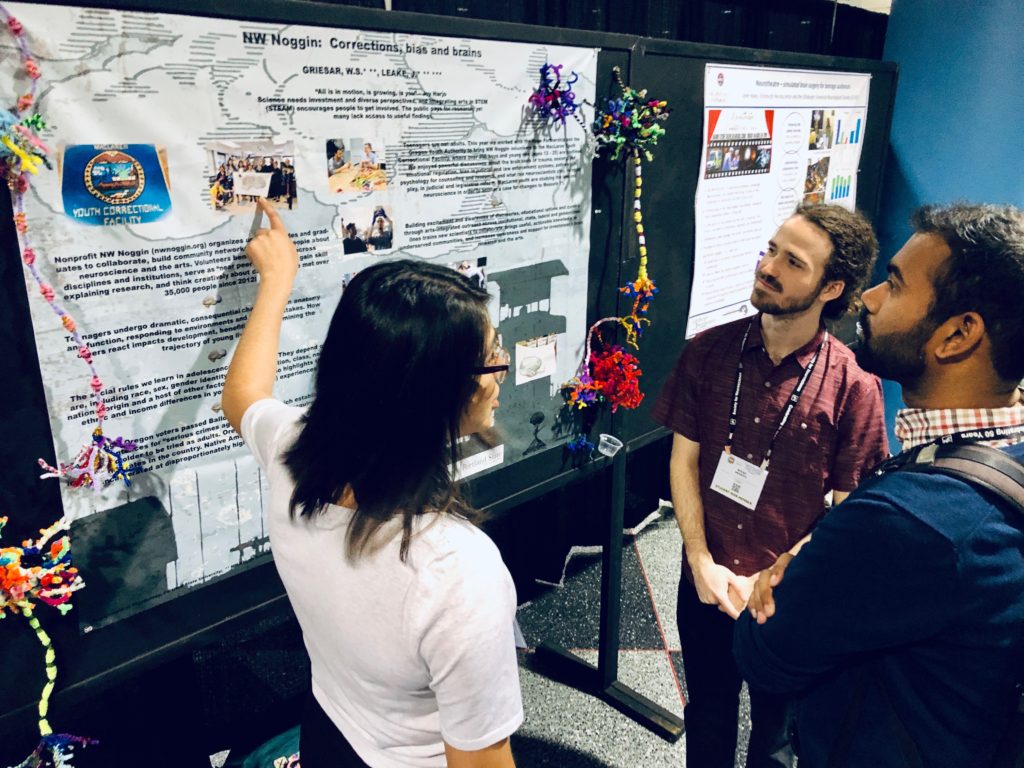 two students stand at a scientific poster while one presents