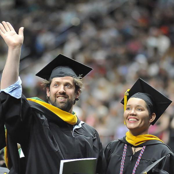 man and woman in cap and gown at commencement