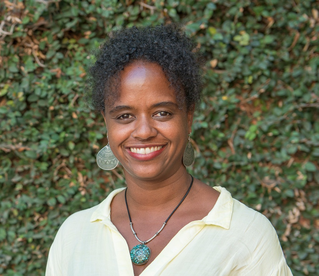 Photo of Rashida Crutchfield smiling and standing in front of foliage.