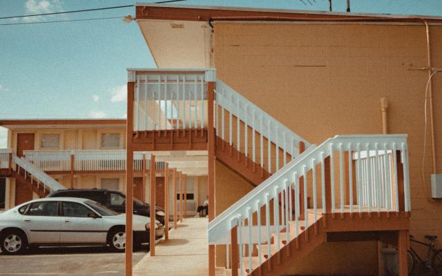 photo of outside stairs leading to a motel entrance with cars in the background