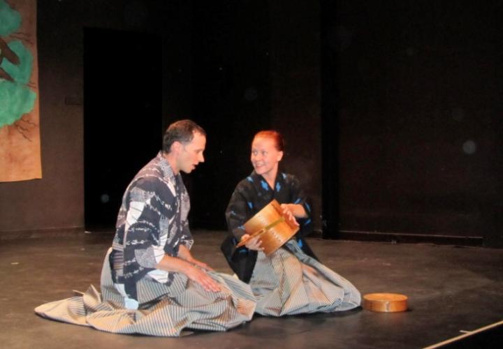 Two performers kneeling onstage