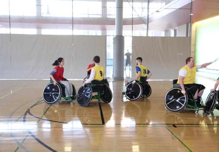 A group of people playing wheelchair basketball in a gym. 