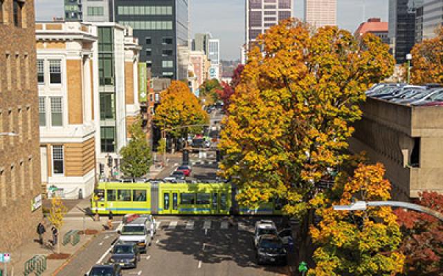 Green streetcar passing Broadway avenue with fall