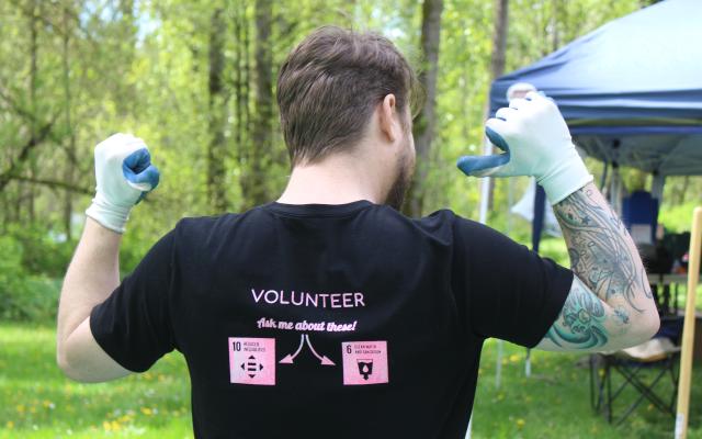 Man pointing to the back of his shirt that reads VOLUNTEER
