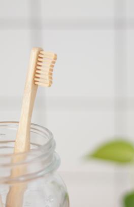 Two toothbrushes in a glass jar on a counter.
