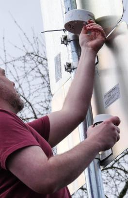 Man installs air quality sensor to the back of a road sign
