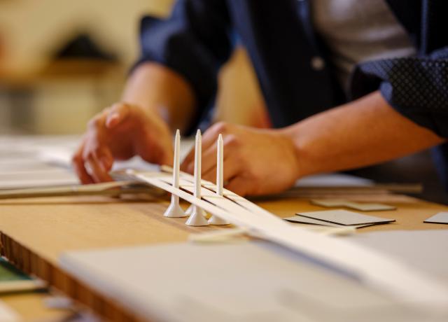 a close up photo of a student building a model of a bridge