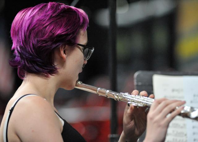 a person with short purple hair plays a flute
