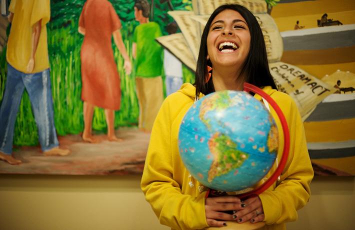 Student laughing while holding a globe