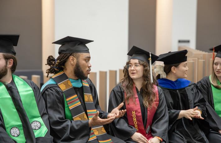 Two graduating students in regalia converse
