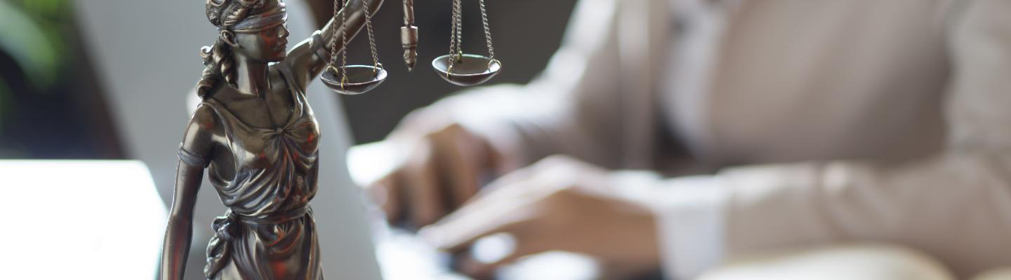 Statue of Justice and lawyer working on a laptop