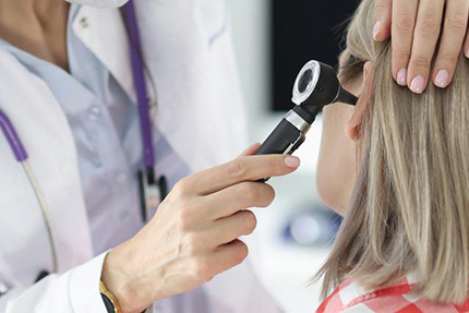A doctor inspects the inside of a patient's ear.