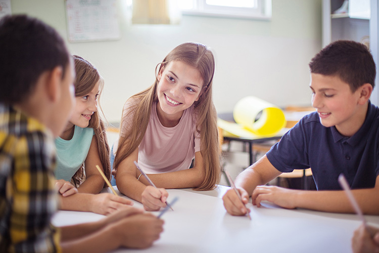 A group of middle school students chat together between assignments.