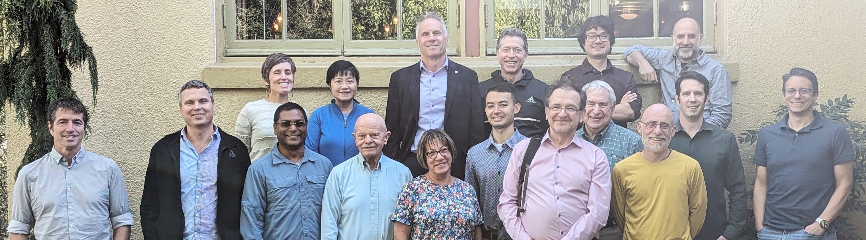 Faculty and Staff of the ECE department gather together in front of a wall. 