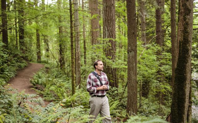 Portland State University environmental science and management graduate student walking in the forest.