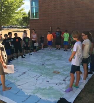 Children standing in circle round edge of Giant Map of Oregon
