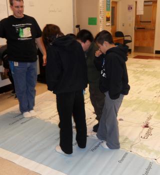 Teacher and small group of kids on giant map