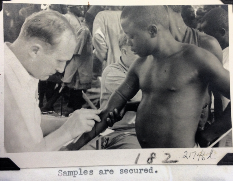white doctor drawing blood sample from African boy