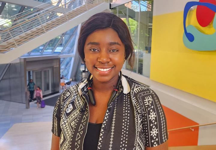 Student stands and poses for a headshot in the Karl Miller Center Atrium.