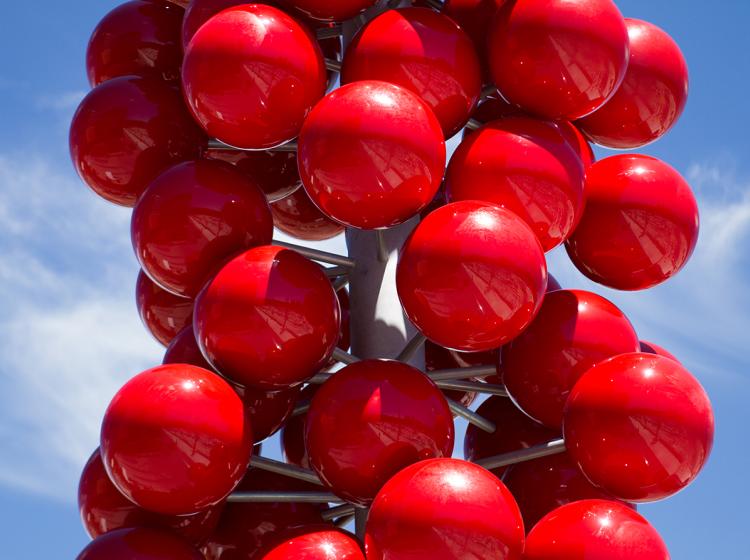 Close-up of the sculpture, showing bright red orbs attached with small poles to a large central pole.