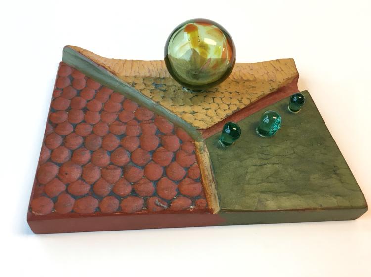 Abstract sculptural artwork consisting of a wooden base colored red, yellow and green, with four attached green glass spheres of various sizes.