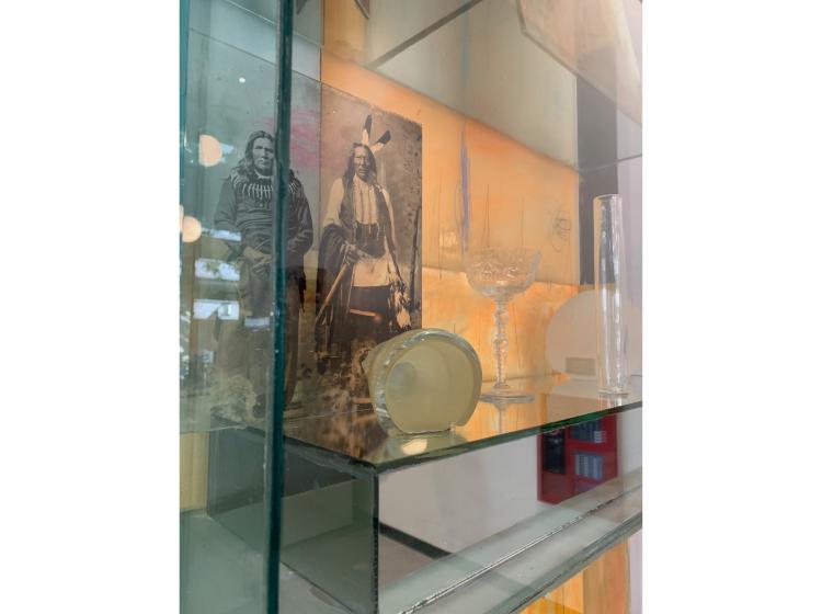 Detail shot of a section of the artwork, featuring a vintage photo of Native Americans alongside a glass goblet and other items