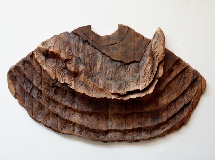 An abstract sculpture made from wood, in a rough organic shape similar to a large polypore fungus