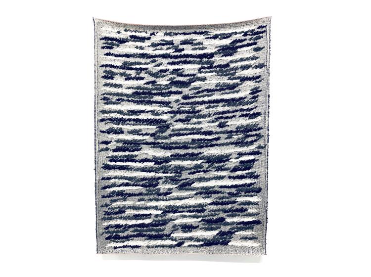 A rectangular textile wall hanging patterned with abstract black, white and grey streaks resembling transmission static