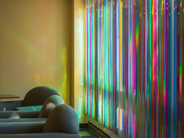 Close-up of a corner of the room, with reflections from the colorful blinds visible on the wall