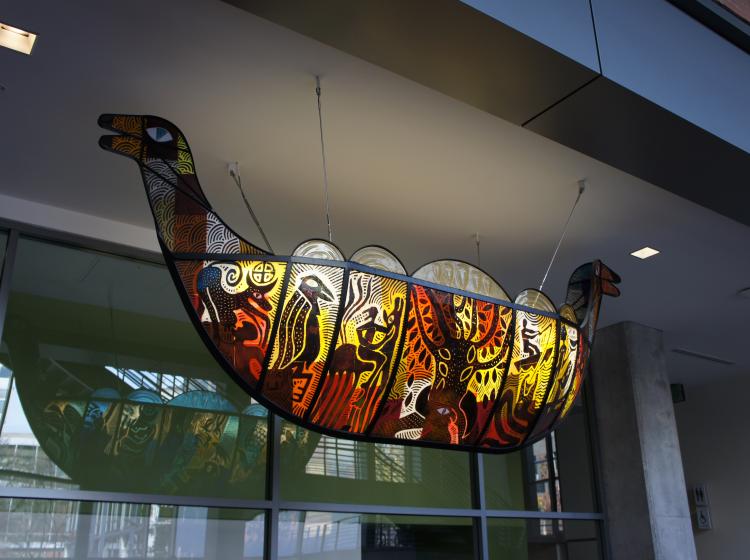 Sculpture of a Viking ship, in iron and colored glass, suspended from ceiling in the ASRC lobby. This side of the sculpture has orange, red and yellow glass