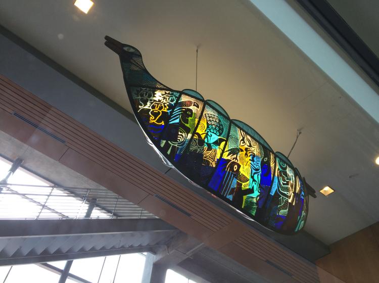 The sculpture is viewed almost directly from underneath. The side with blue glass is visible.