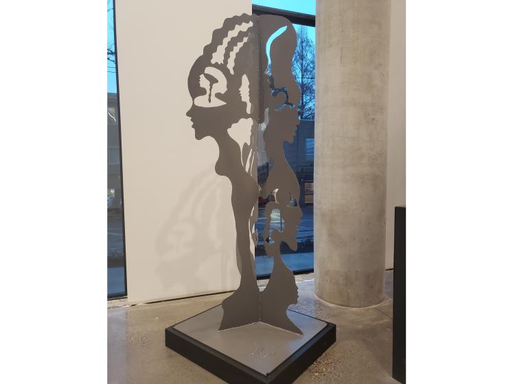 Sculpture of an abstracted human figure, composed of three conjoined black two-dimensional "cutout" elements