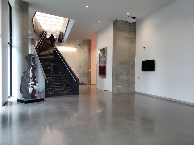 The artwork is seen in a wide shot showing the Vanport Building lobby and stairway. The artwork is at center, hung on the wall