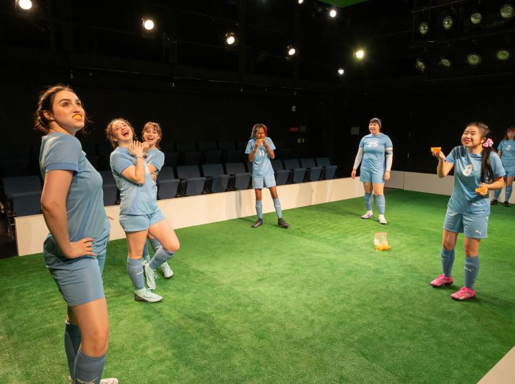 Cast of PSU Theater's "The Wolves" dressed in soccer costumes with orange peels in their mouths.
