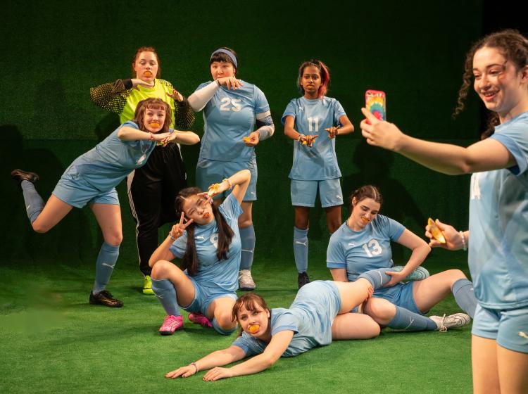 Cast of PSU Theater's "The Wolves" dressed in soccer costumes with orange peels in their mouths.