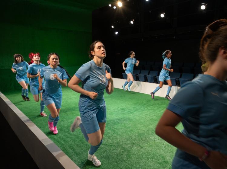 Cast of PSU Theater's "The Wolves" dressed in soccer costumes running laps.