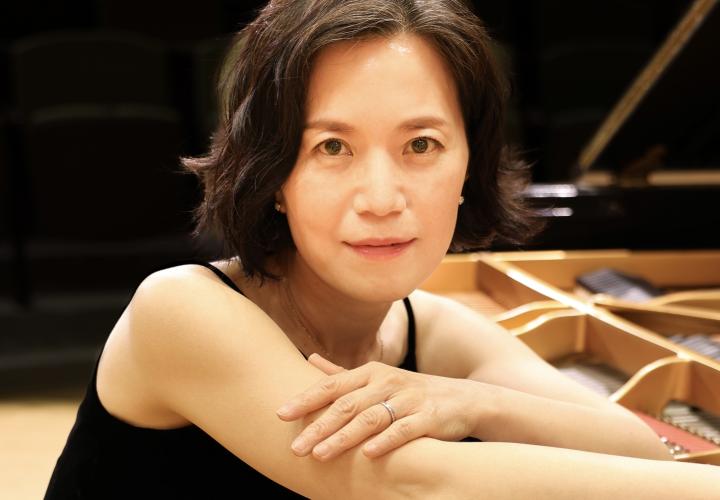 Headshot of pianist Julia Hwakyu Lee leaning on a piano.