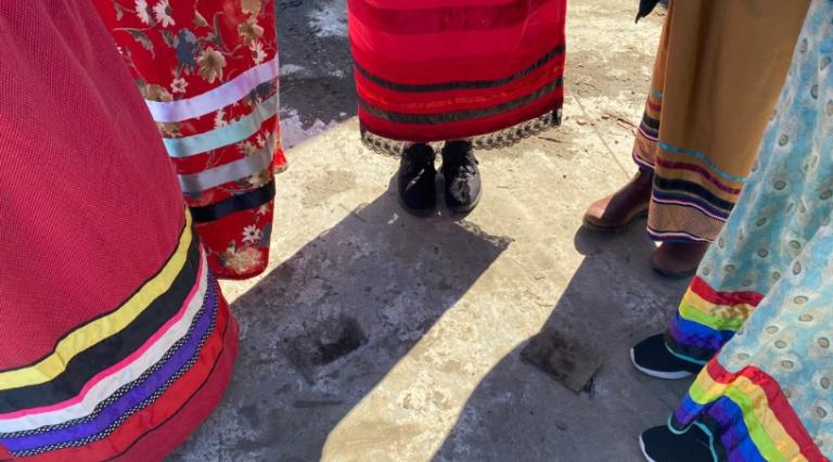Feet of five people wearing indigenous clothing