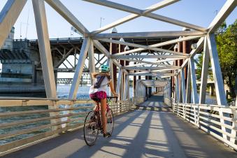 A PSU student riding a bike through a bridge bike path next to the river.
